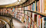 Curved shelves of colourful books along a library walkway
