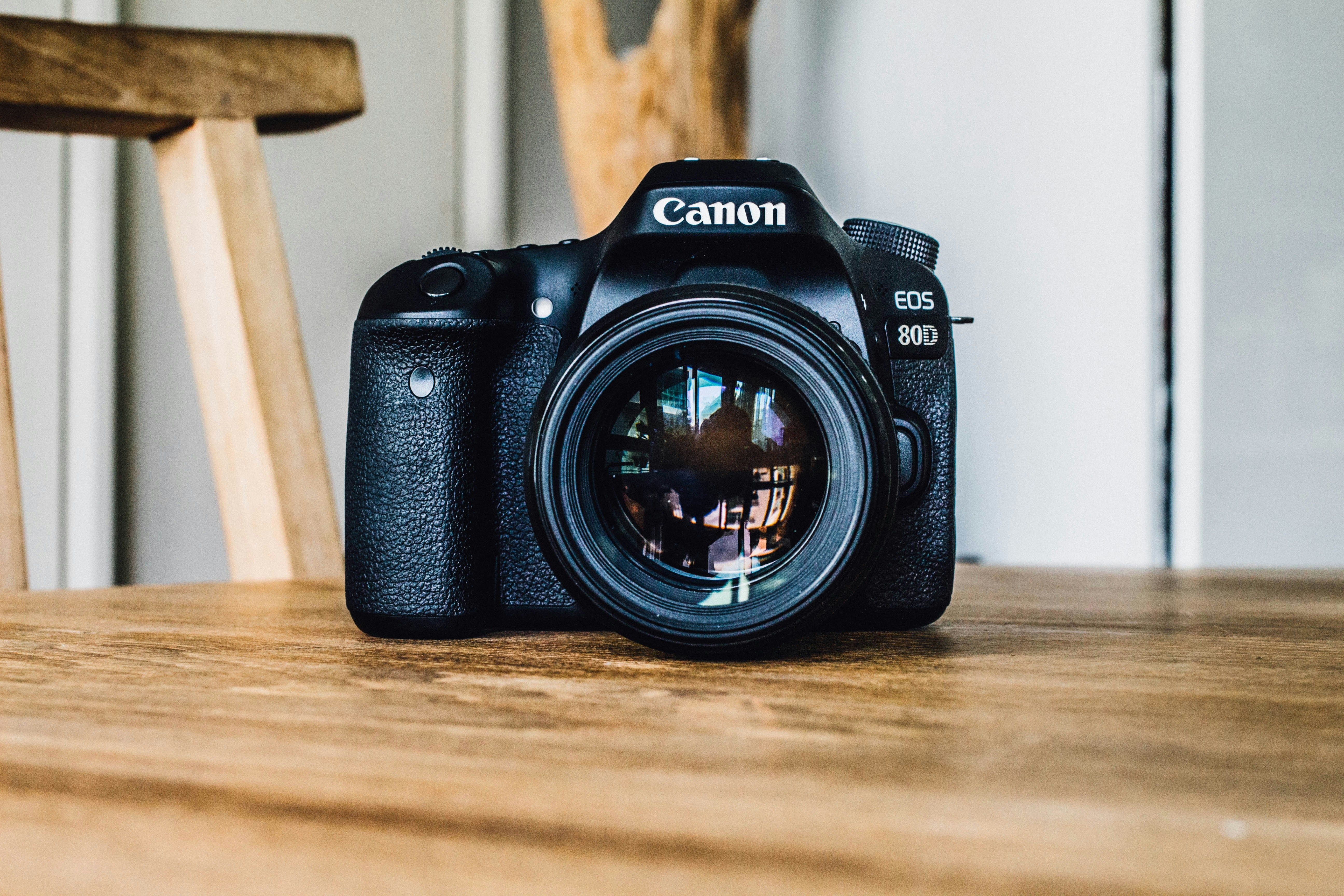 A Canon EOS 80D camera sitting on a wooden table