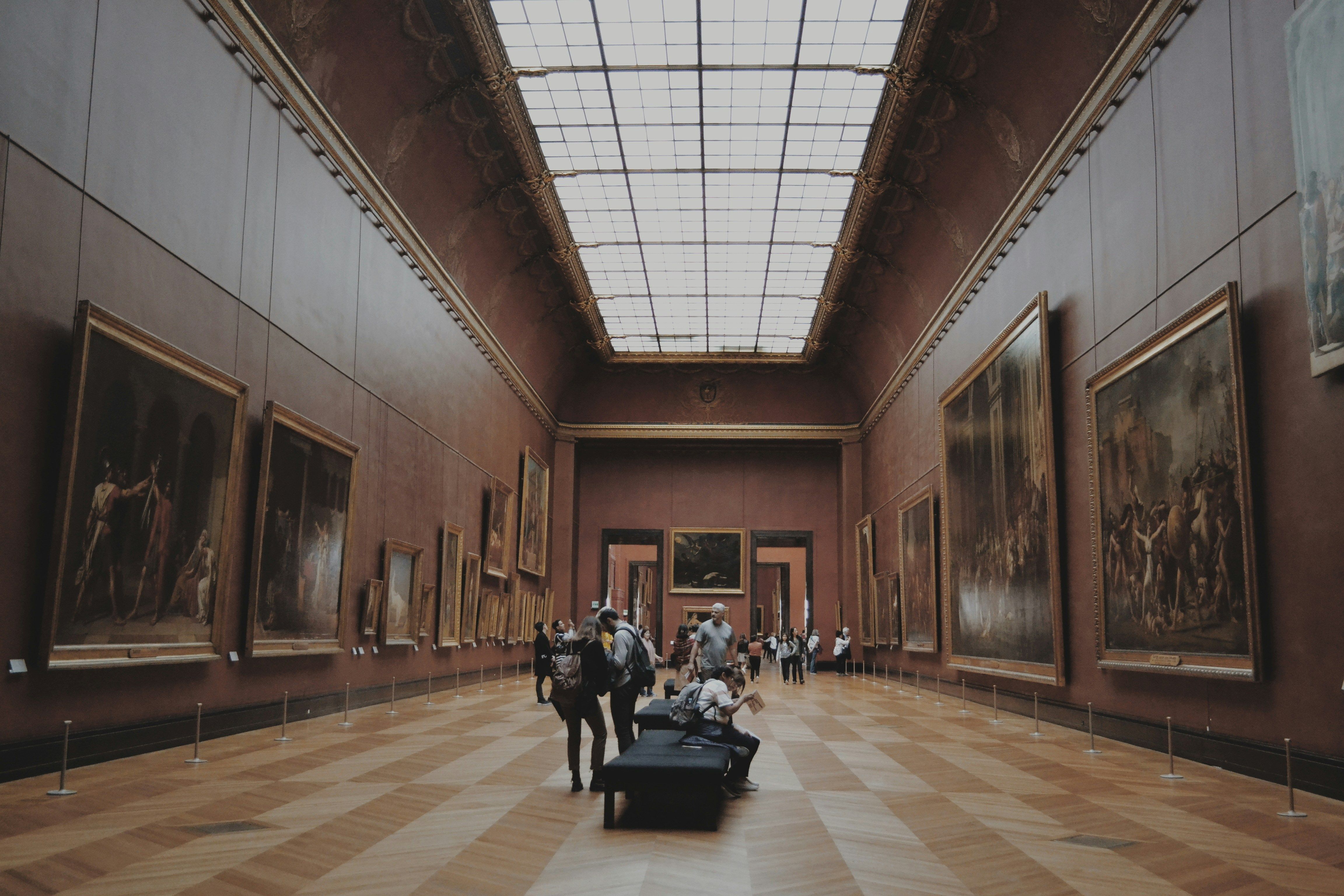 A grand gallery hall lined with large framed paintings