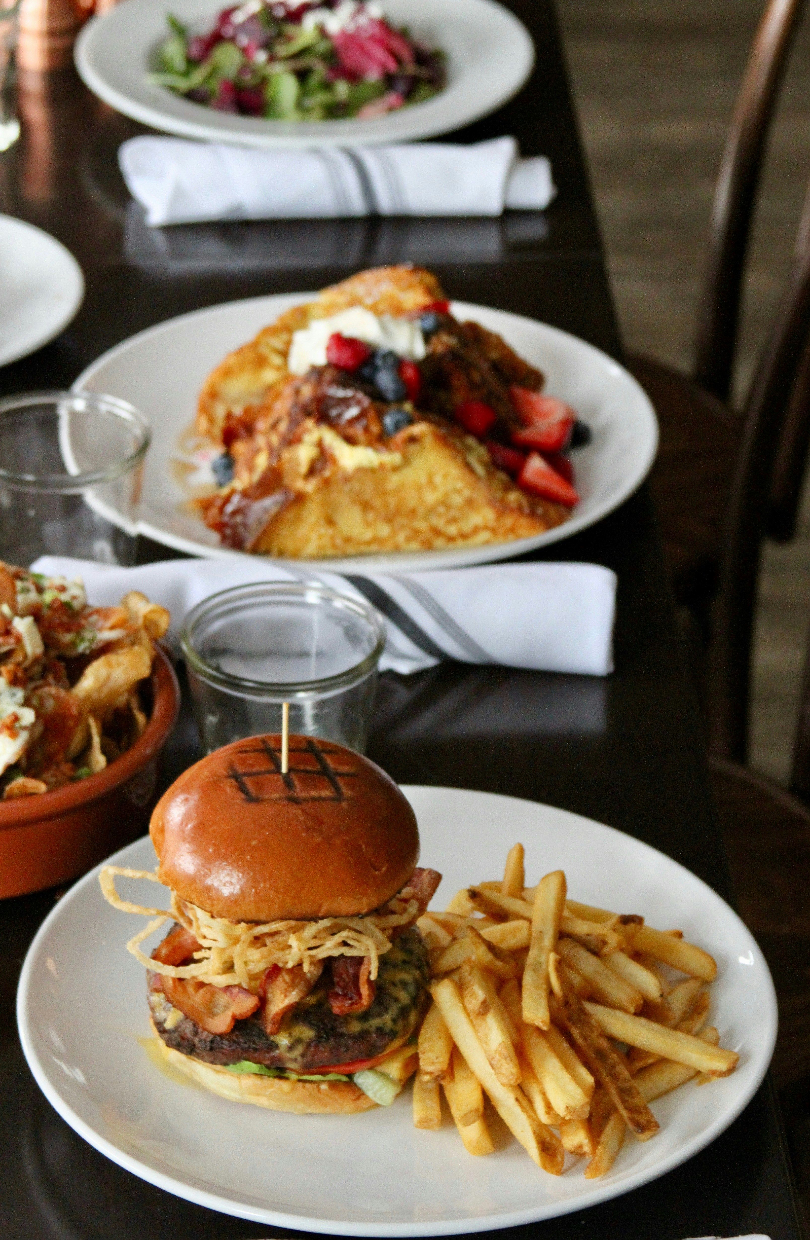 A burger with crispy onions and bacon next to a plate of fries