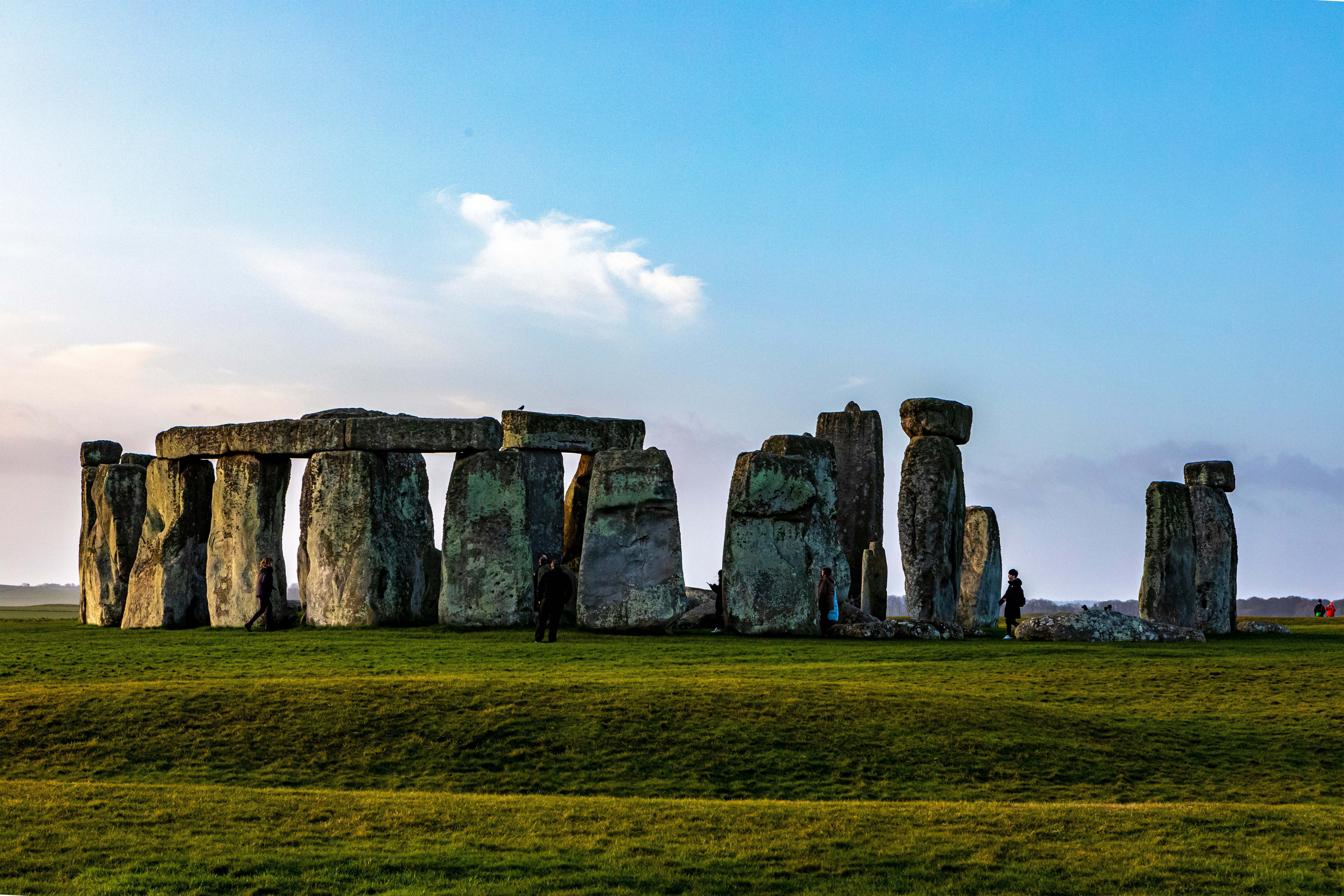 Stonehenge standing in a green field under a blue sky